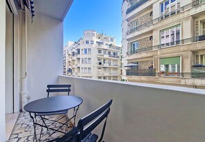 A balcony with a table and chairs, overlooking a row of multi-story buildings. - New! N&J - ROSSINI CHARM - Central - Balcony (Nice)