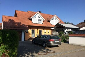 A two-story house with a car parked in the driveway. - Holiday apartment with 2 bedrooms (Langenargen)