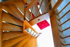 Eine hölzerne Wendeltreppe mit rotem Teppich auf der obersten Plattform.