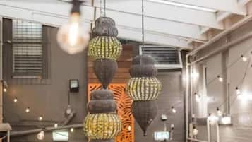 Un interior moderno con lámparas colgantes, una pared decorativa de madera y una mesa con plantas en macetas.