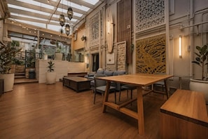 A spacious indoor area with a wooden floor, seating arrangements, and decorative elements. - London Gate Backpackers Hostel (Potts Point)
