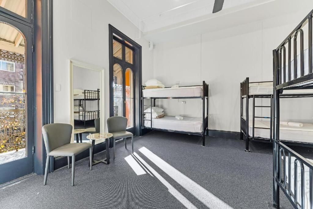 A room with bunk beds, a small table, two chairs, and a window with a view of buildings.