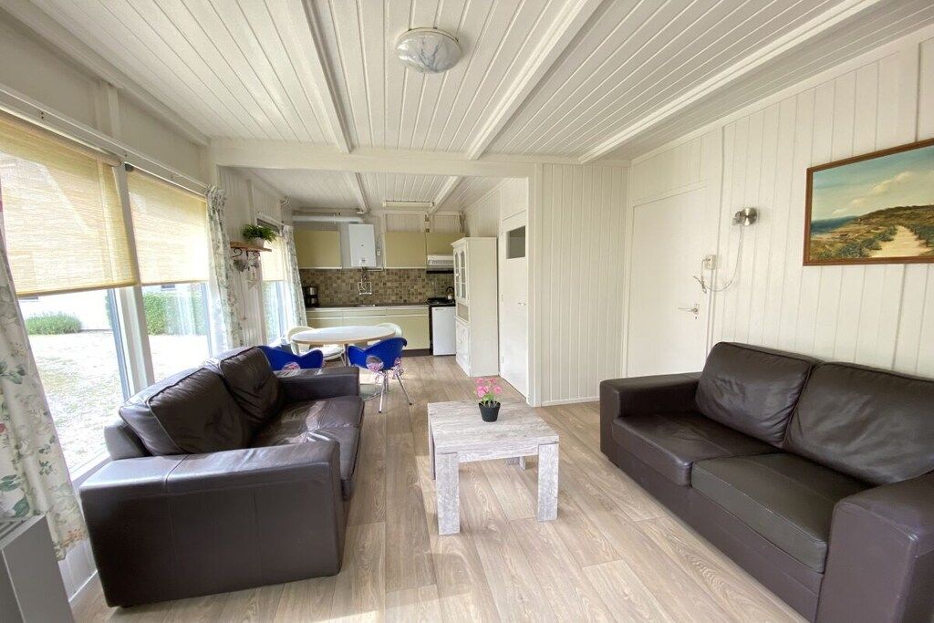 A living room with two sofas, a coffee table, and a view of the kitchen.