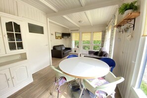 A room with a round table, chairs, a sofa, and a television. - Type C "Zee, Bos en Duin" (Zoutelande)