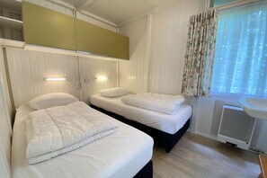 A room with two beds, a window with curtains, a radiator, and a sink. - Type C "Zee, Bos en Duin" (Zoutelande)