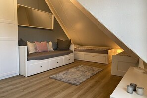 Une chambre à coucher de style « loft », avec un plafond en pente, des rangements intégrés et une petite table agrémentée d’objets décoratifs.