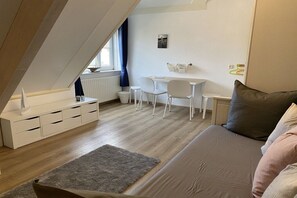 A modern, well-lit room with a loft-style ceiling, a sofa, a small table, a chair, and a radiator. - Lieblingsplatz de Banjaard (Kamperland)