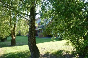 A residential area with a lawn, trees, and a house in the background. - Holiday apartment with 2 bedrooms (Gronau)