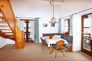 Ein Essbereich mit einem Holztisch, Stühlen, einer Bank und einer Pendelleuchte.