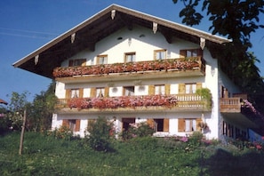 A multi-story building with balconies adorned with flowers, wooden shutters, and a traditional architectural style. - Holiday apartment with 2 bedrooms (Samerberg)