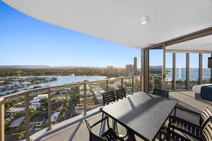 Varanda com mesa e cadeiras, vista para a cidade e para a água.