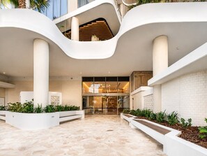 A modern building with a curved exterior, a central staircase, and a glass entrance. - Luxury Broadwater Retreat at Lagoon Main Beach (Main Beach)