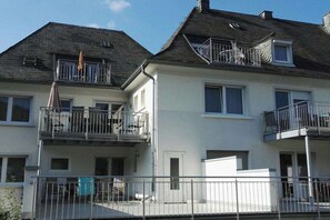 A multi-story residential building with balconies, a flat roof, and a gated entrance. - Apartment with balcony overlooking the castle (Bernkastel-Kues)