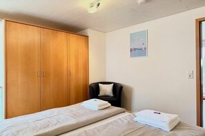 A room with a bed, a chair, a wardrobe, and a poster on the wall. - Holiday apartment with 1 bedroom (Nonnenhorn)