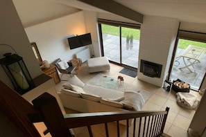 A modern living room with a sofa, a fireplace, and a television. - Forest cottage by the sea (Sint Maartensvlotbrug)