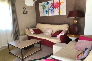 A living room with a sofa, a coffee table, a lamp, and a world map on the wall. - gîte in St-Sauveur-de-Cruzières (Commune)