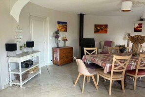 A dining area with a table set for four, surrounded by chairs, a television, and artwork on the walls. - gîte in St-Sauveur-de-Cruzières (Commune)