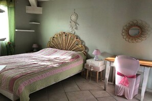 Quarto com cama, mesa de cabeceira, cadeira e objetos decorativos.