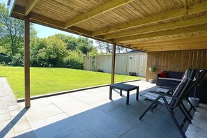A covered patio area with a table and chairs, a wooden ceiling, and a view of a grassy yard. - Bavelds Home - Denekamp (Denekamp)