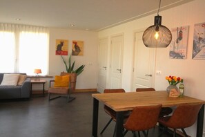 Ein Essbereich mit einem Holztisch, Stühlen, einer Hängelampe und Bildern an den Wänden.