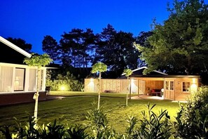 A residential property with a well-maintained lawn, a wooden deck, and a house with a visible garage and attached garage. - Bavelds Home - Denekamp (Denekamp)