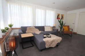 Ein Wohnzimmer mit einer Couch, einem Couchtisch, einem Beistelltisch, einer Stehlampe und einem Sessel.