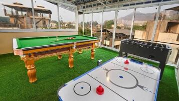 Un área recreativa interior con mesa de billar y mesa de hockey de aire.