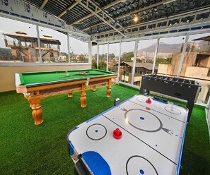 Un área recreativa interior con mesa de billar y mesa de hockey de aire.