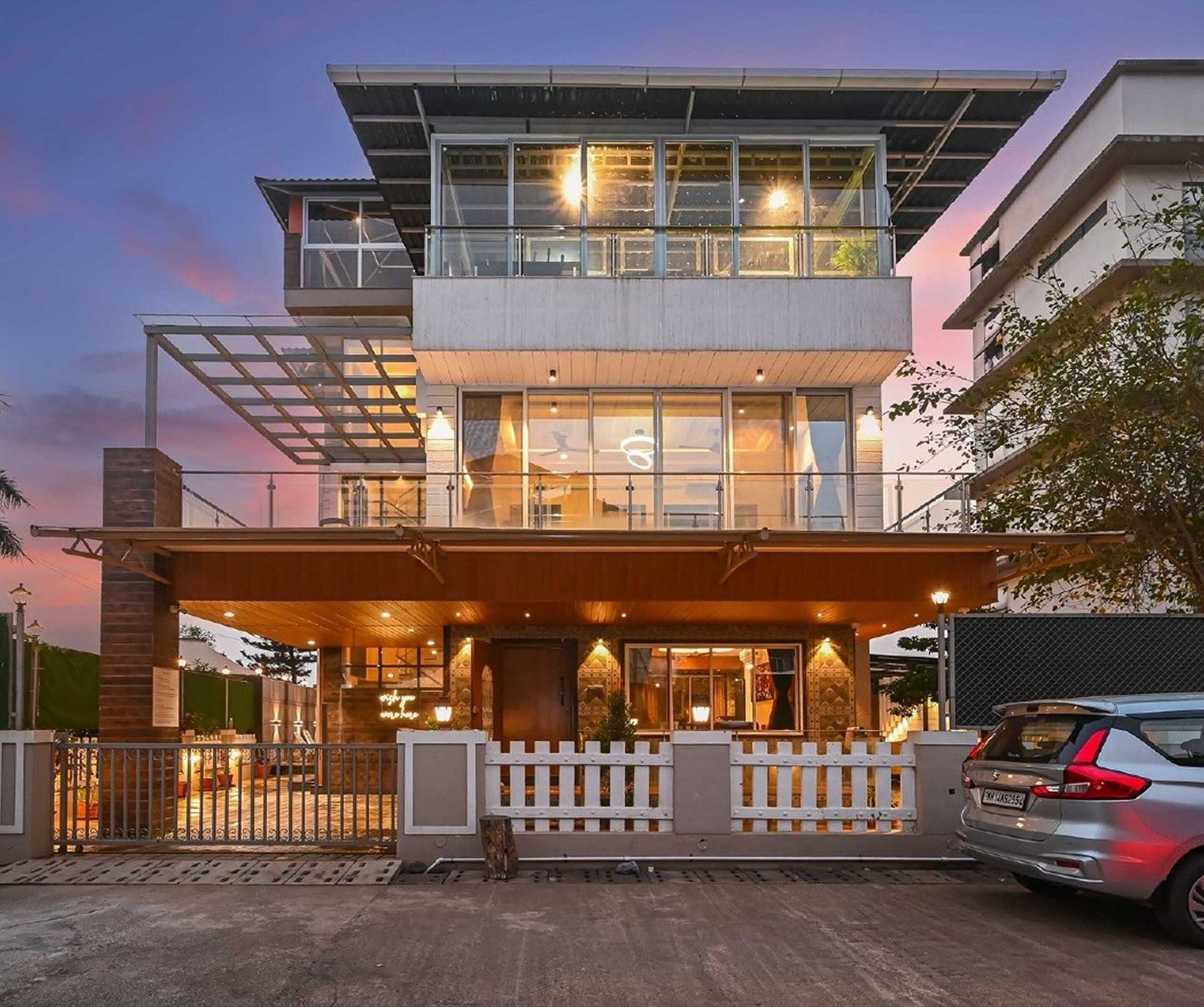 A modern two-story building with a glass facade, a wooden entrance canopy, and a gated driveway.