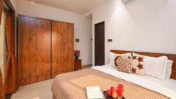 Ein Hotelzimmer mit Bett, Kleiderschrank, Nachttisch und Klimaanlage.
