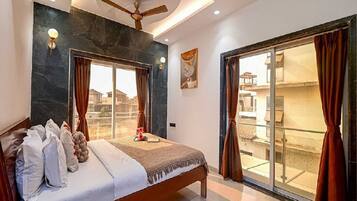 Un dormitorio con cama, cortinas, ventilador de techo y vistas a través de un ventanal corredero.
