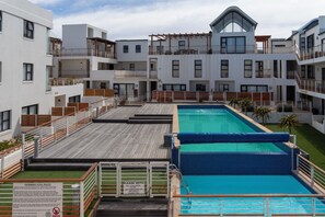 Un hôtel moderne doté d’une piscine, de nombreux balcons et d’une terrasse sur le toit.