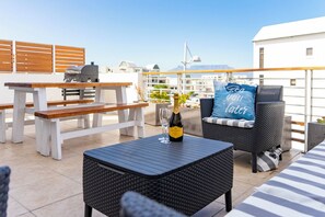 Une terrasse sur le toit avec des sièges extérieurs, une table et une bouteille de champagne.