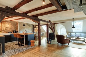 A spacious loft with exposed wooden beams, a kitchen with a stone backsplash, and a cozy seating area with a fireplace. - Old wine press house (Bernkastel-Kues)