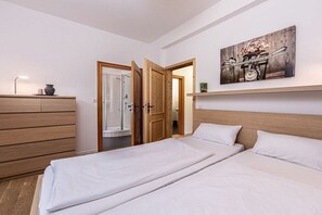 A bedroom with two beds, a wooden dresser, a shower, and a painting on the wall. - Leni holiday apartment (Bischofswiesen)