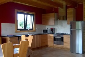 A compact kitchen with wooden cabinets, a stainless steel refrigerator, a microwave, and a gas stove. - by the sea between Paimpol and Bréhat (ploubazlanec)