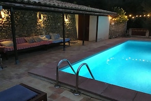 A swimming pool with a stone wall and a covered seating area with cushions. - Holiday home with 2 bedrooms (Puigpunyent \/ Mallorca)