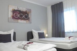 A hotel room with two beds, a painting on the wall, and a window with curtains. - Holiday apartment with 1 bedroom (Saarbrücken)