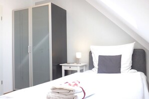 Une chambre d’hôtel avec un lit, une table de chevet, une armoire et une lampe.