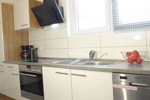 A modern kitchen with white cabinets, a stainless steel sink, a black oven, and a dishwasher. - Holiday apartment with 1 bedroom (Saarbrücken)