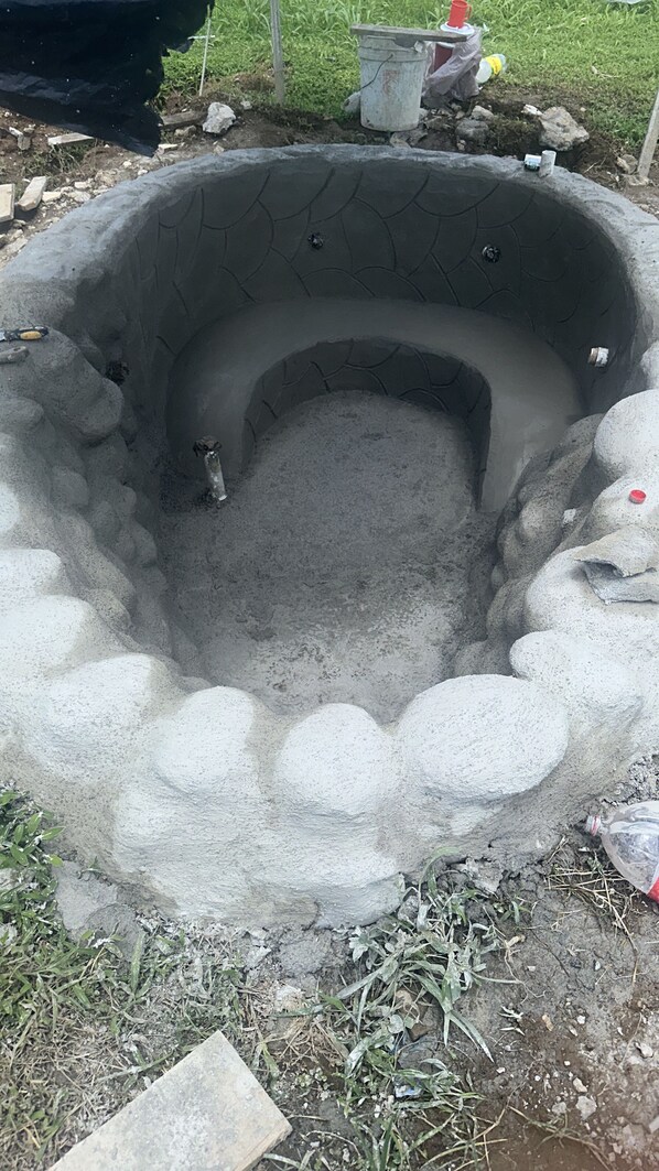 A circular outdoor structure with a central hollow area, surrounded by a raised, textured edge.