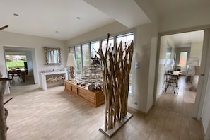 Een ruime woonkamer met een groot raam, een houten eettafel en een moderne open haard.