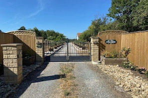 Ein verschlossenes Tor mit einem Kiesweg, der zu einem Gebäude führt.