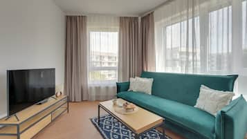 Ein modernes Wohnzimmer mit Fernseher, einem blaugrünen Sofa und einem Couchtisch.