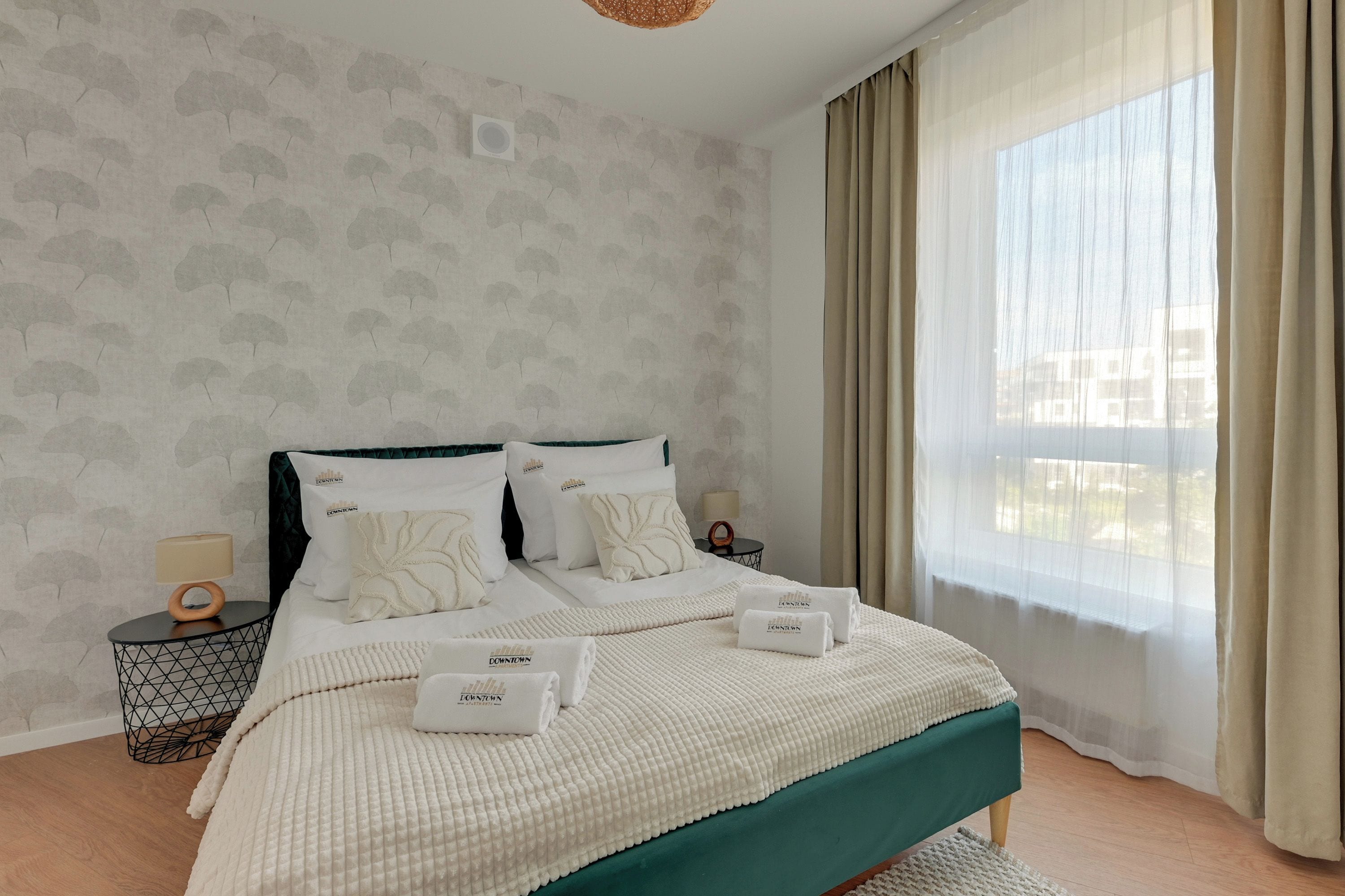 Una camera d'albergo con un letto, due comodini, una lampada e vista sull'esterno.