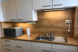 A compact kitchen with a microwave, sink, and wooden countertop. - Holiday apartment with 2 bedrooms (Altdorf-Rasch)