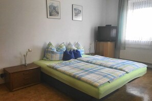 A bedroom with a bed, a nightstand, a television, and two framed pictures on the wall. - Holiday apartment with 2 bedrooms (Altdorf-Rasch)