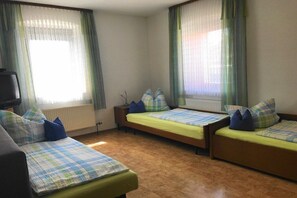 Una stanza con due letti, un divano e una televisione.