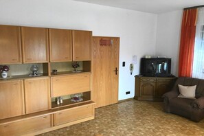 Un soggiorno con mobili in legno, una televisione e un divano marrone.