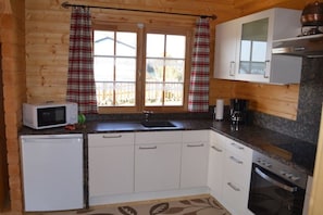 A compact kitchen with a microwave, sink, and oven. - Holiday home with 1 bedroom (Adelschlag Ortsteil  Möckenlohe)